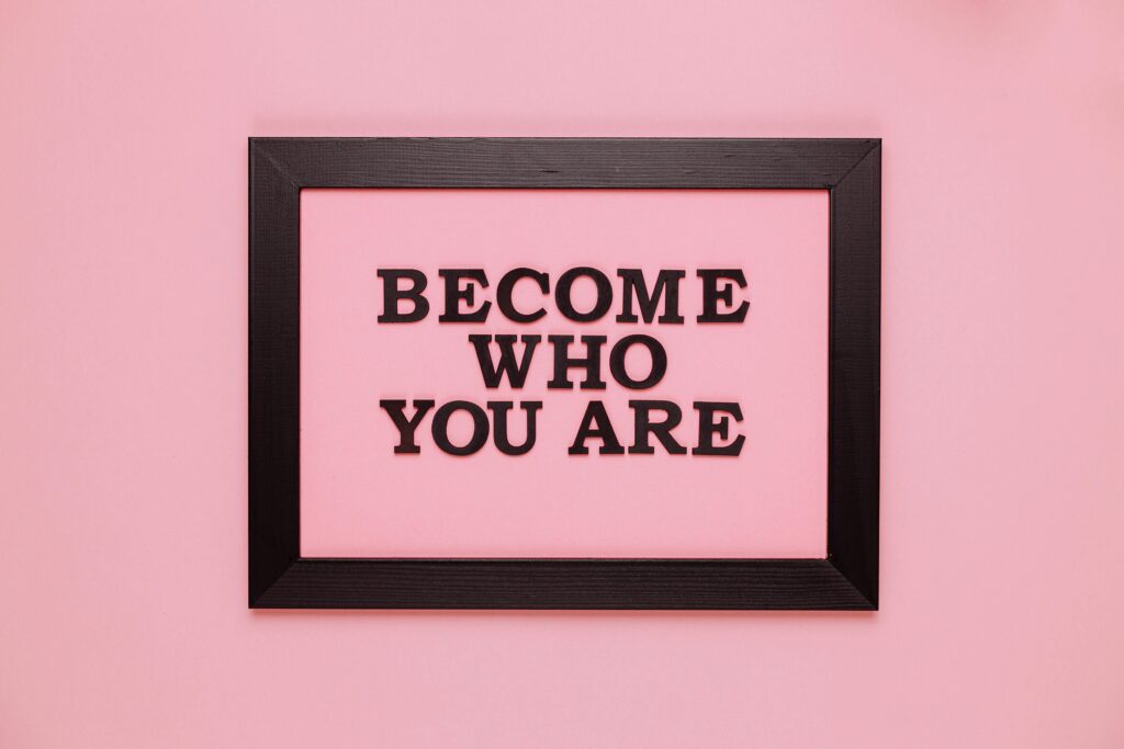 Inspiring quote 'Become Who You Are' framed on a vibrant pink wall, perfect for encouragement.